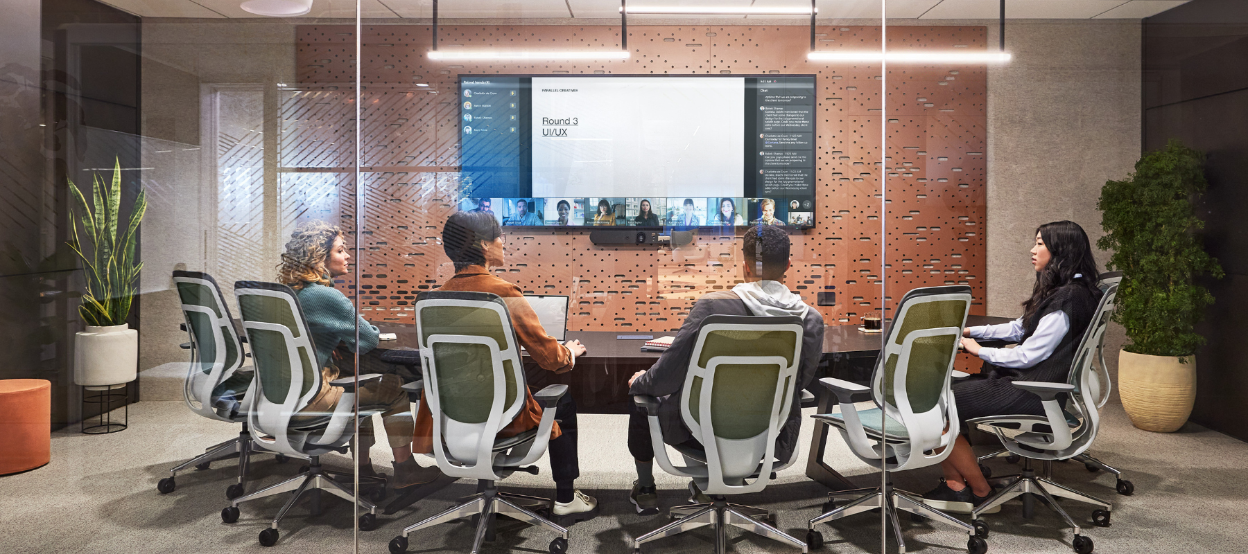 a group of people in a meeting room utilizing a video conferencing system with remote coworkers